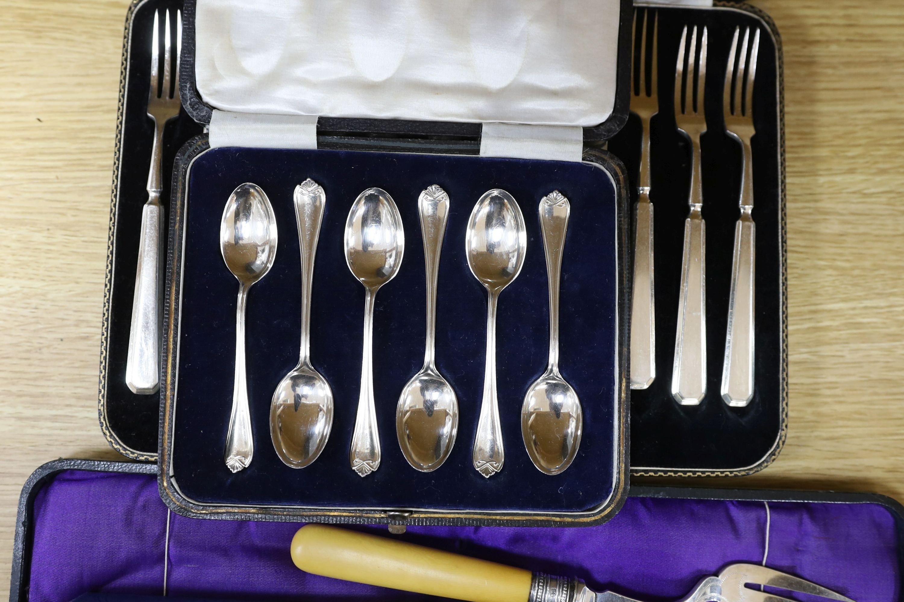 A cased pair of servers, and serving fork, cased silver coffee spoons, royal commemorative spoon, trefid coffee spoon, plated set of dessert knives and forks